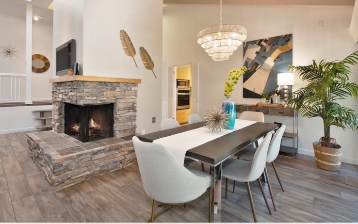 Stacked stone corner fireplace with fire burning in a modern Vermont home serviced by Mad River Valley Chimney Services