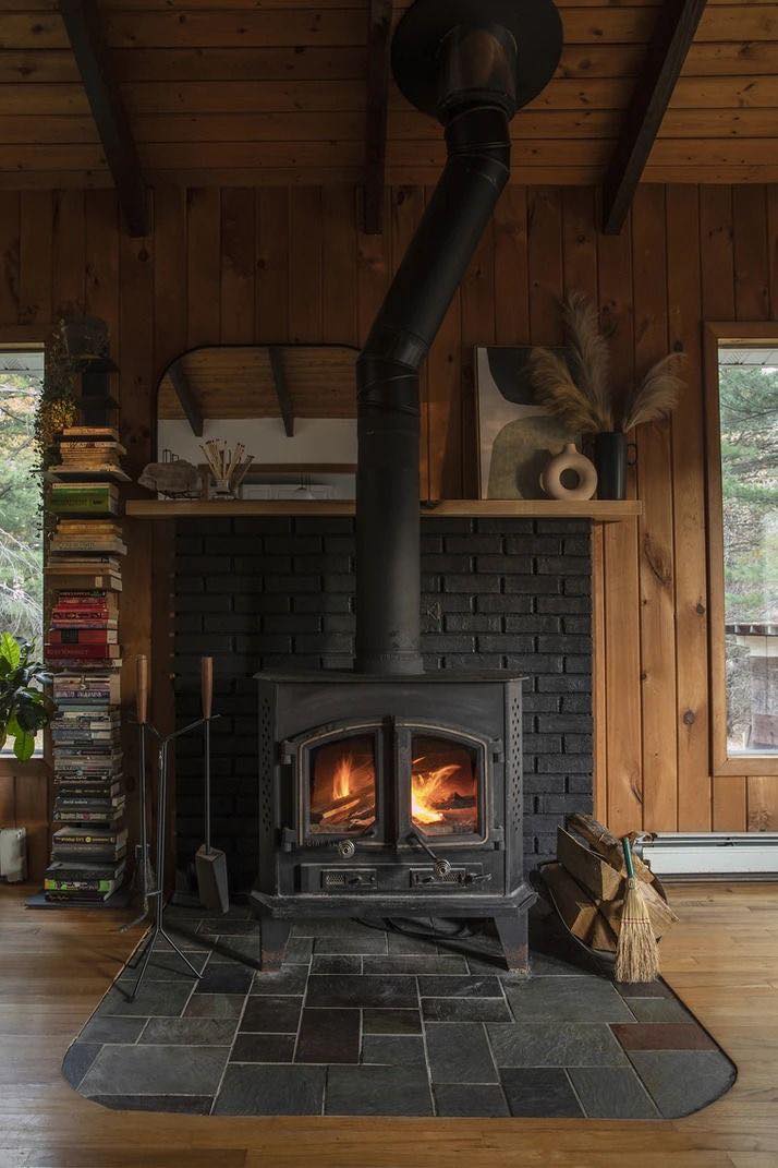 Cast iron wood stove with fire burning on slate hearth in a Vermont cabin swept and inspected by Mad River Valley Chimney Services